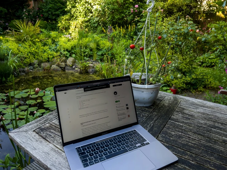 laptop open on table on wooden deck outside