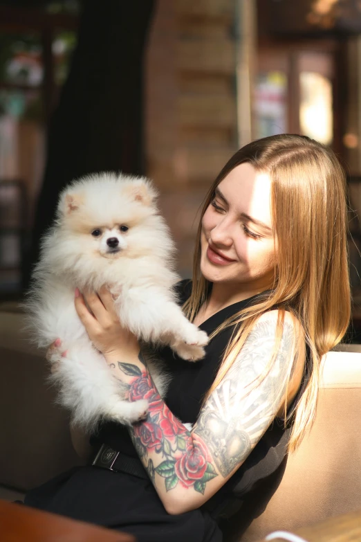 a woman holding a small white dog on top of a couch