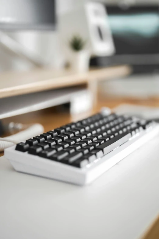 a black and white keyboard with a monitor in the background