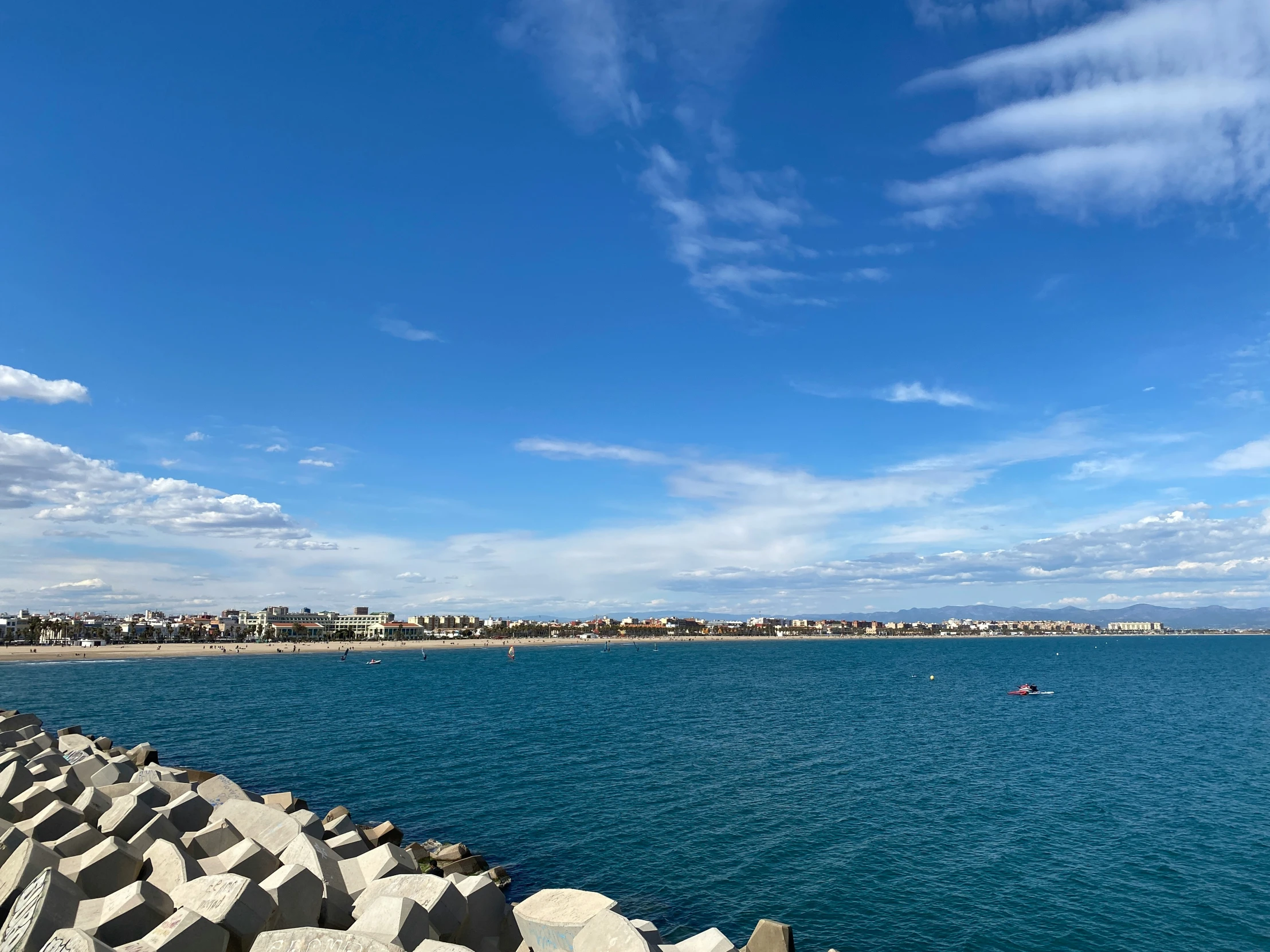 the view from a dock looking at a beach with boats out in the water