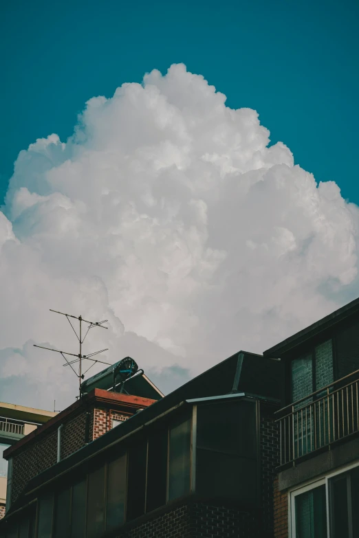 a building with windows, a balcony and a cloudy sky above it