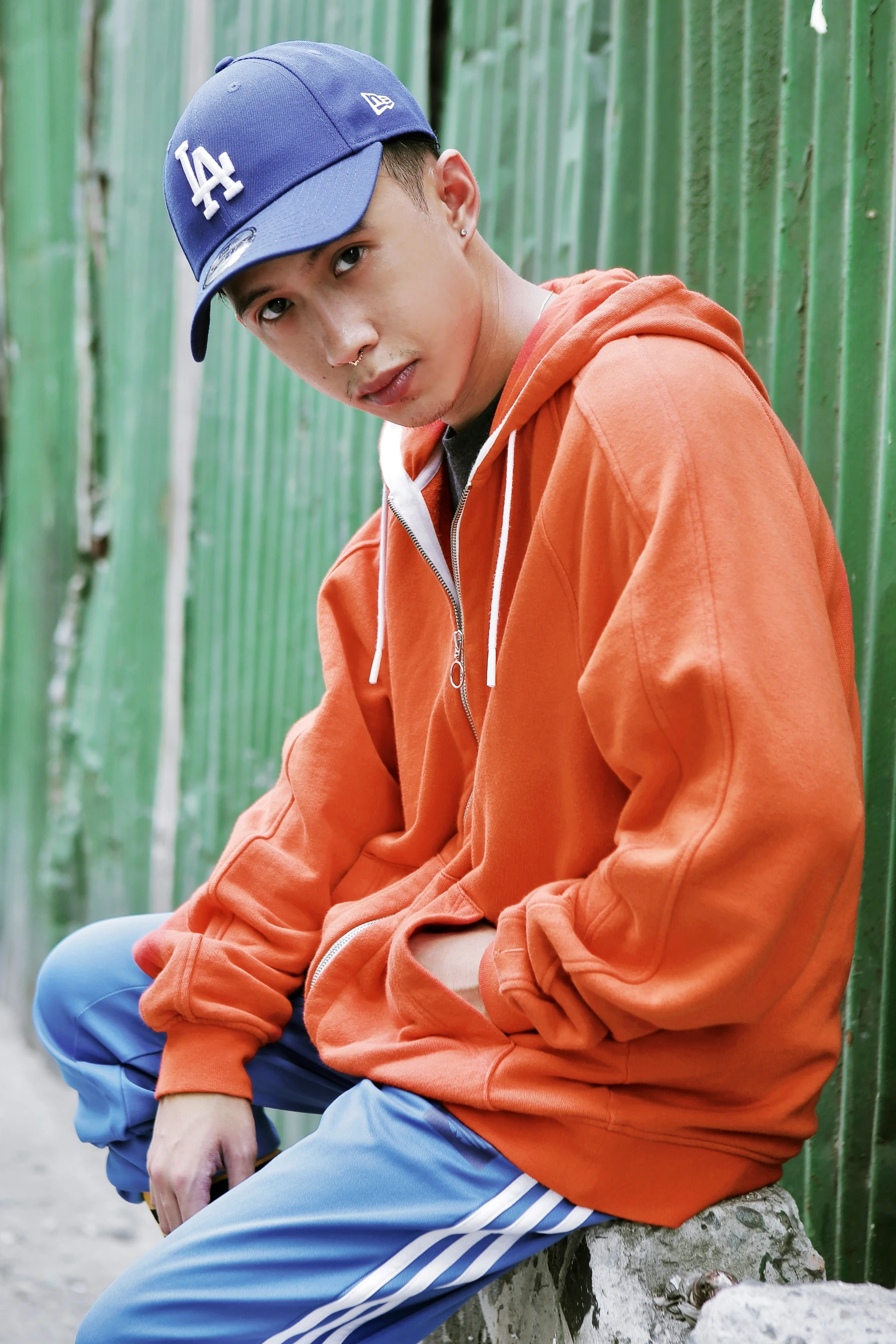 boy sitting on concrete corner in front of green wall