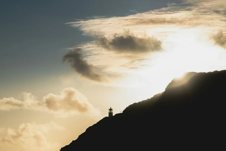 the silhouette of a lighthouse on top of a mountain