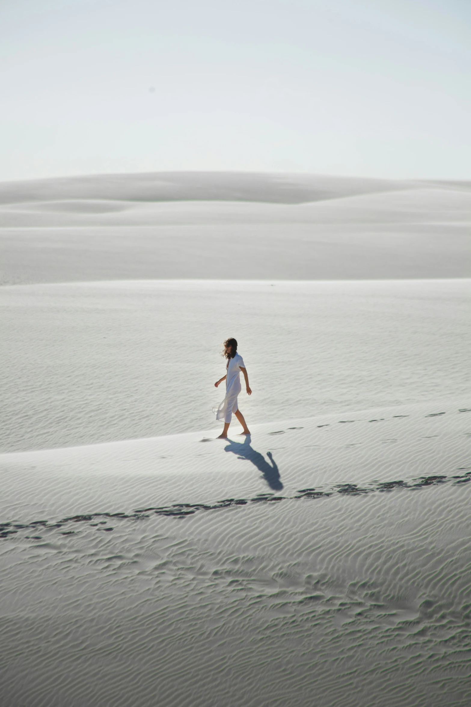 a person walking across a big sandy beach