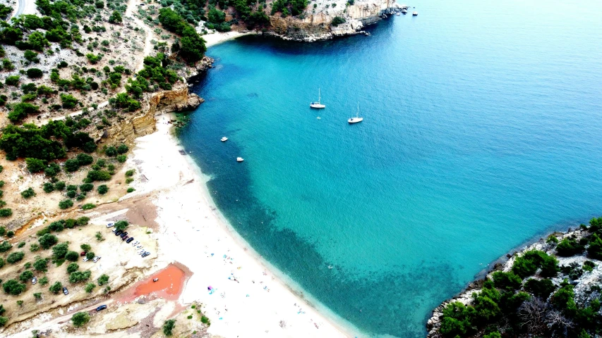 an aerial view of a blue body of water with two boats docked on it