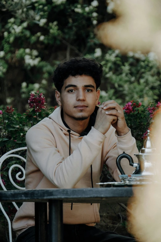 a young man sitting at an outdoor dining table