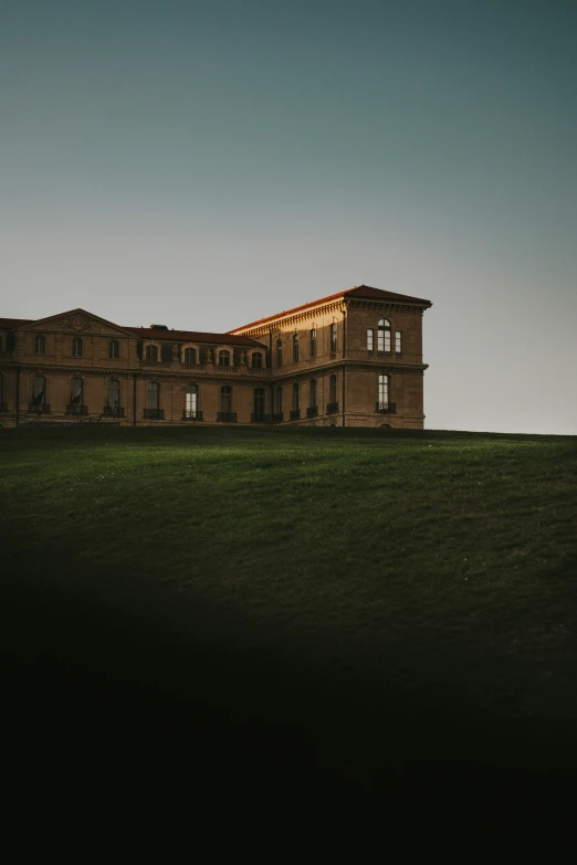 a building is sitting on top of a hill at dusk