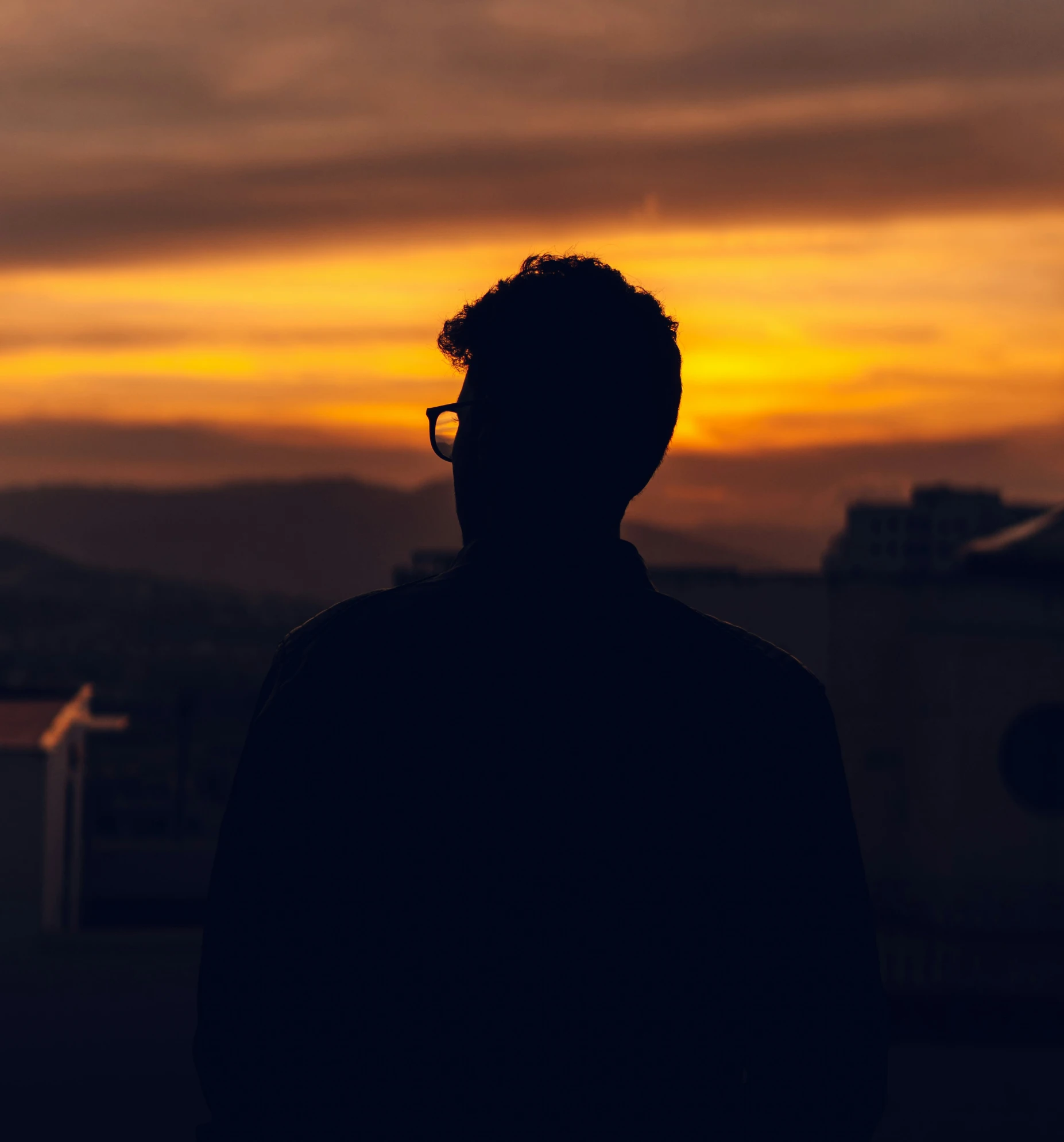 the silhouette of a man with eyeglasses is shown at sunset