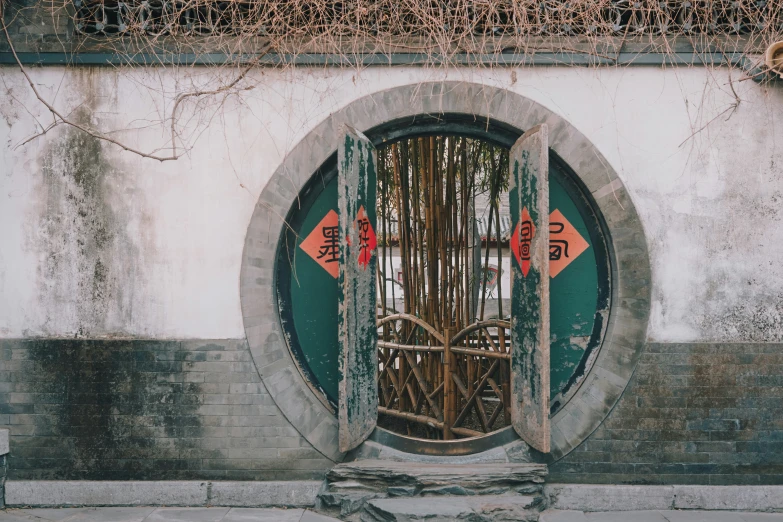 an open, circular door with chinese red and orange signs on it