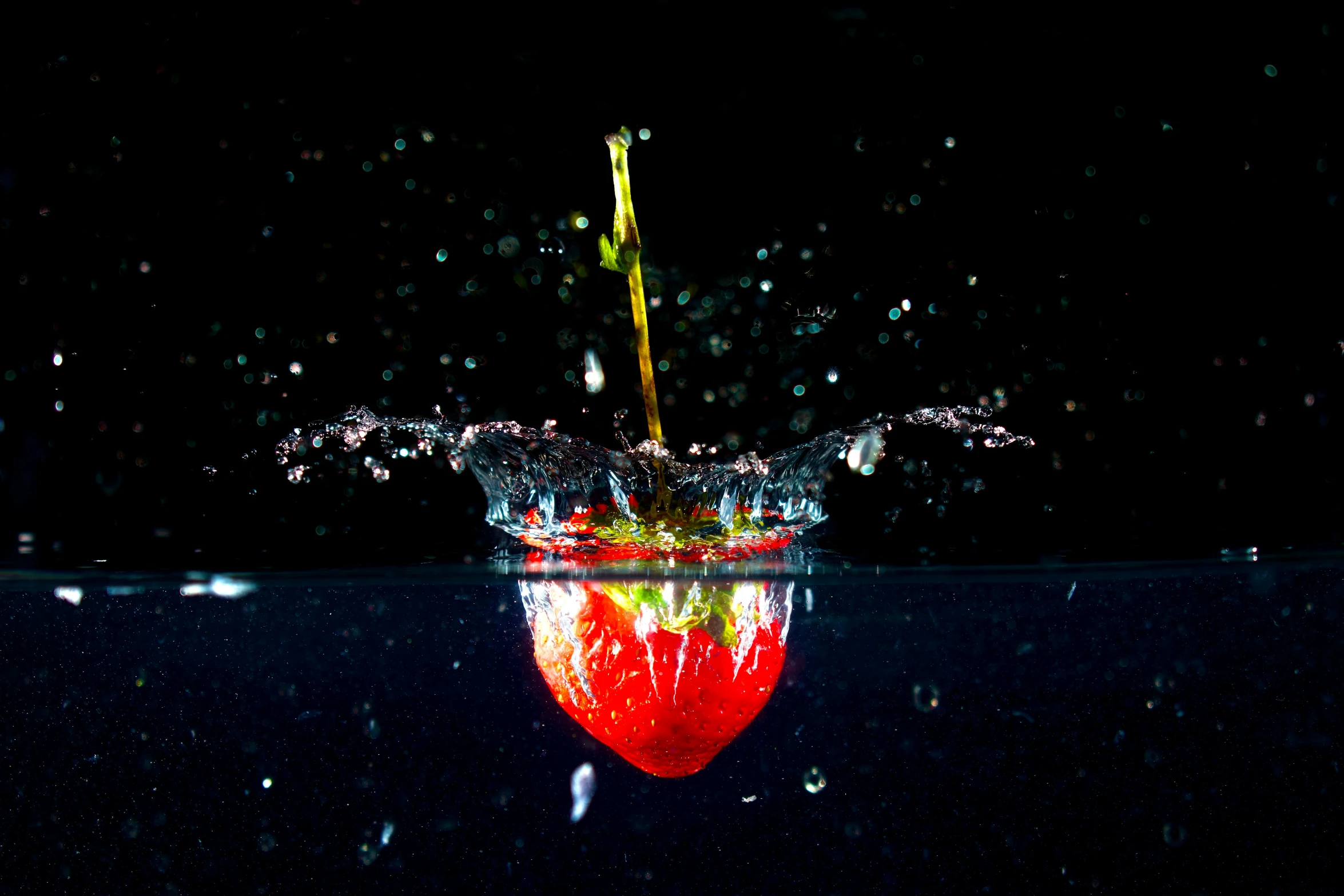 a red apple is floating in water with drops