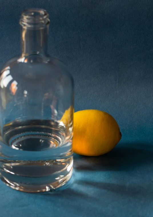 a bottle and a lemon sit on a table