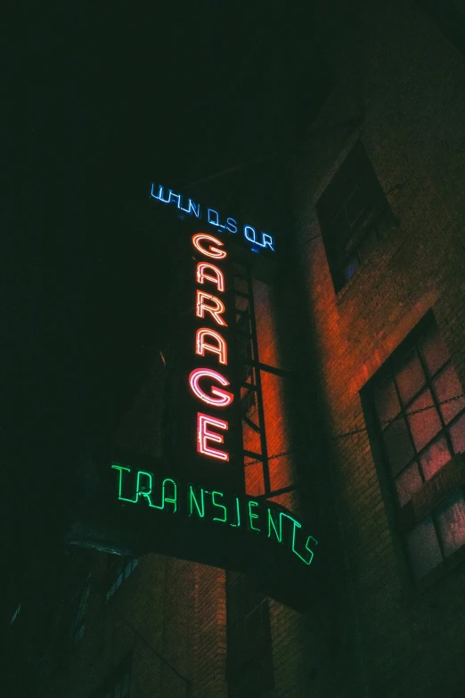 a tall building with lights on top and a neon sign above it