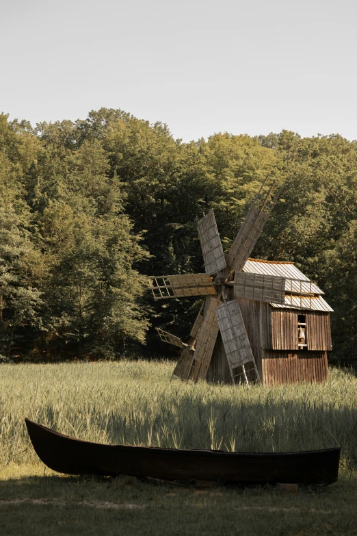 a windmill with a boat in the grass by it