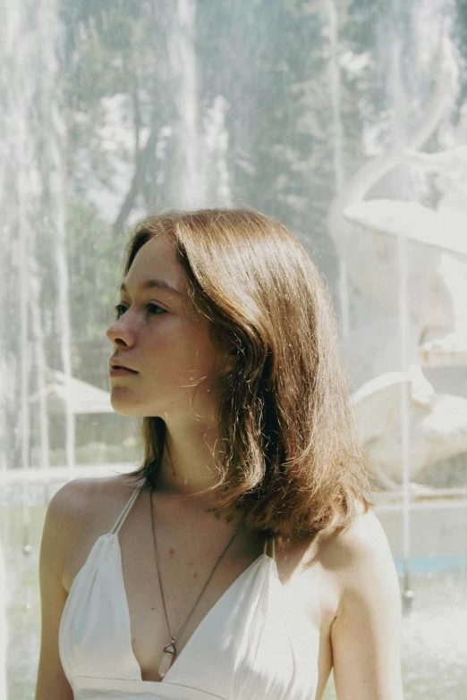 a beautiful woman wearing a white dress by a fountain