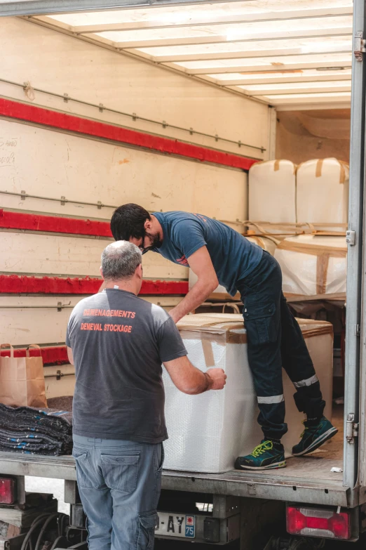 two men unloading supplies from the back of a truck