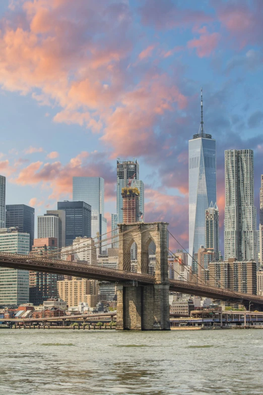 a boat rides past a bridge overlooking city skyline