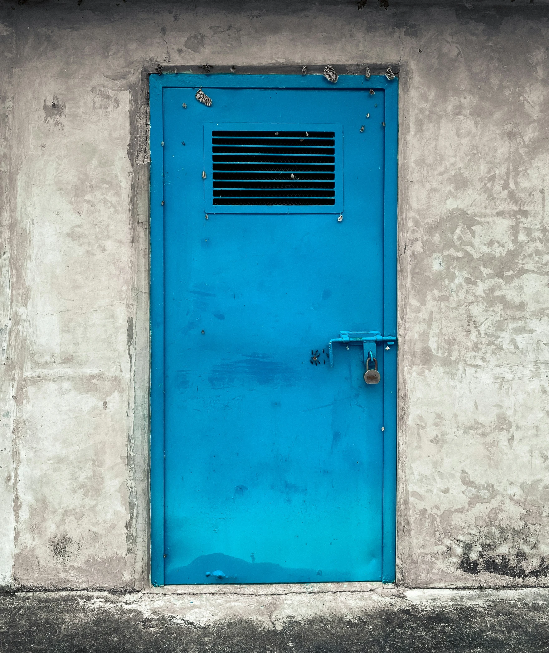 a closed blue door sits in front of a tan wall