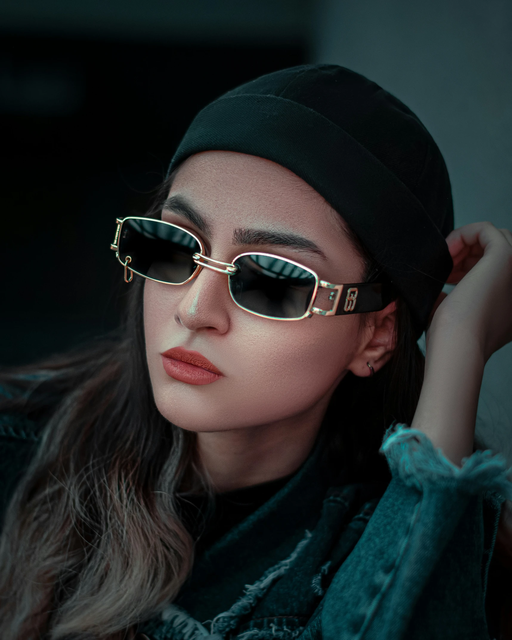 a young woman is sitting outside in sunglasses and a beanie