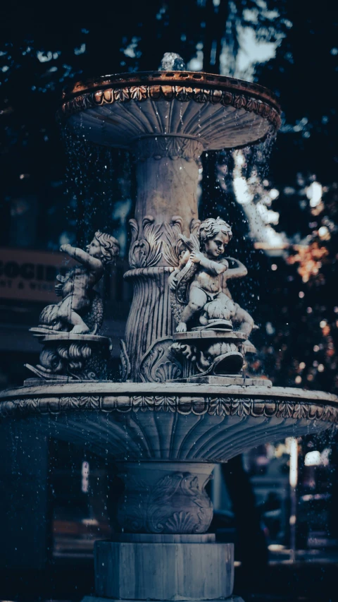 an outdoor fountain with statues of women and men surrounding