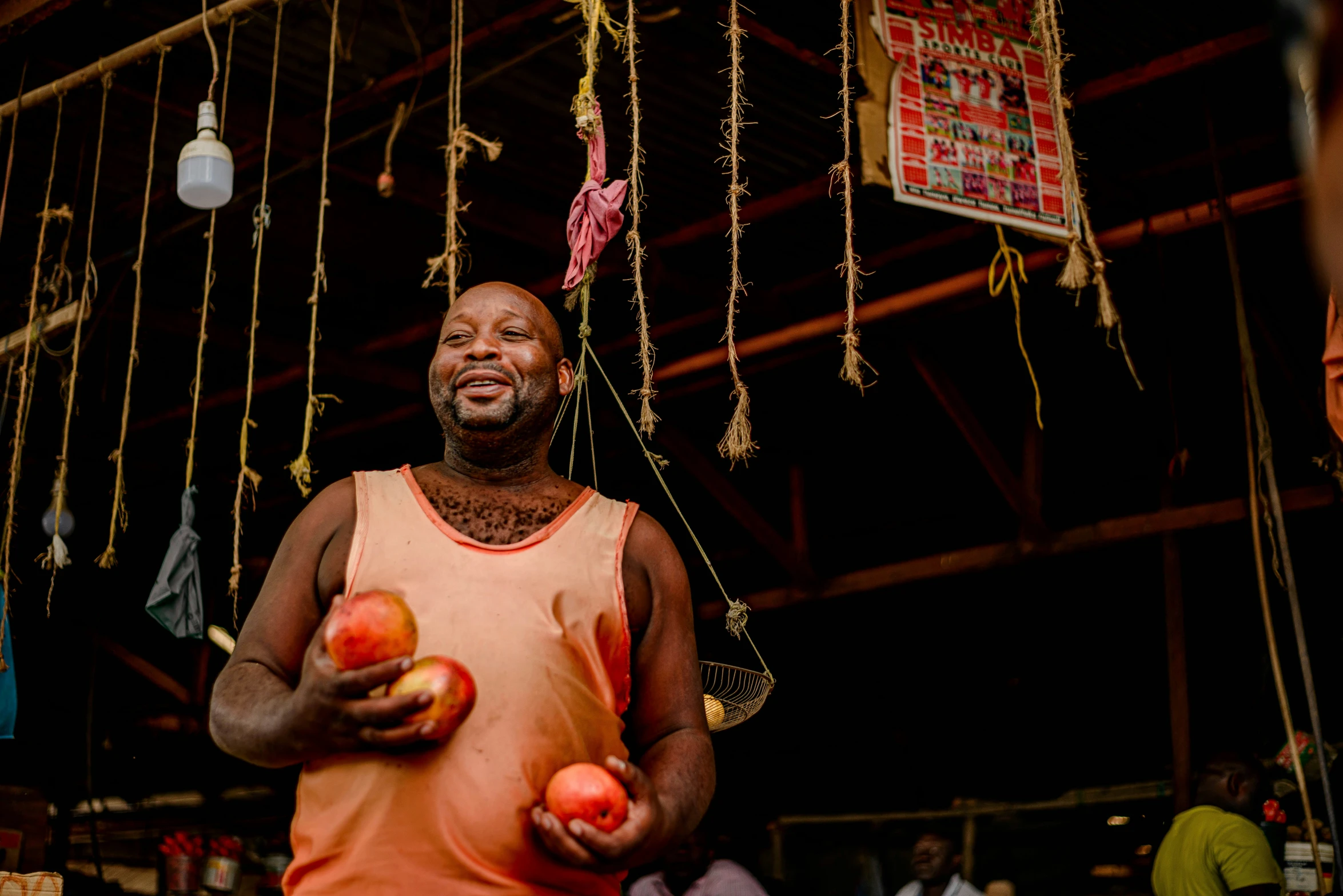 a man holds apples under strings hanging from a building