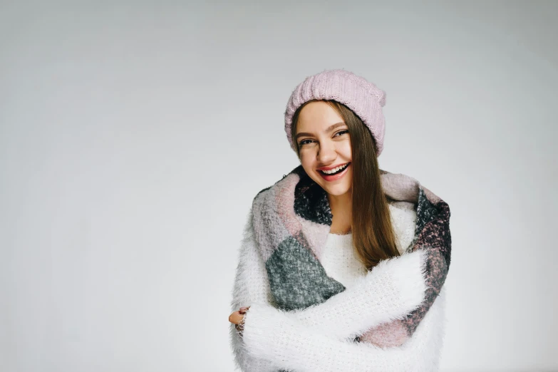 woman in knitted sweater and hat smiling with arms wrapped around