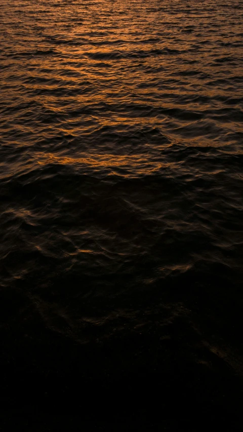 the view of a small sailboat sailing through a calm sunset