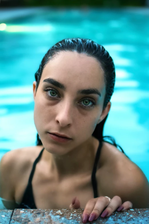 a young woman in a swimming pool looks up at the camera