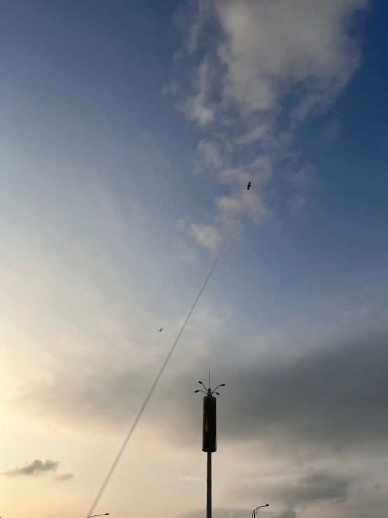 a contrail in the sky above a street light