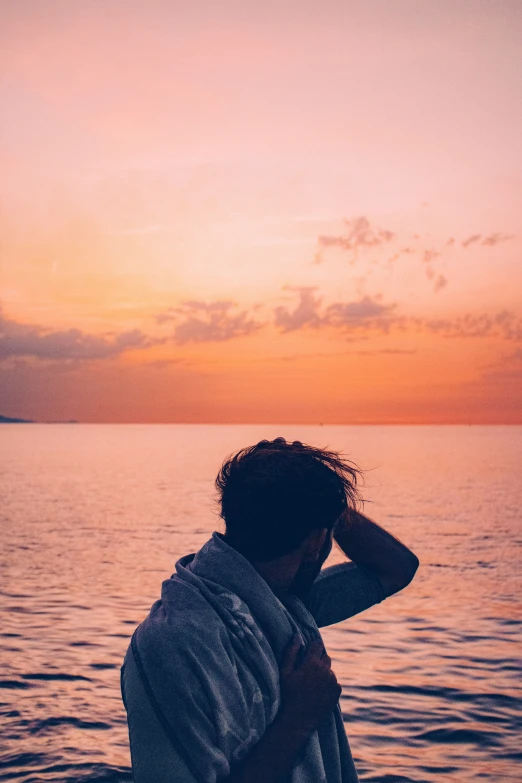 a person on the water at sunset with a towel over their shoulder