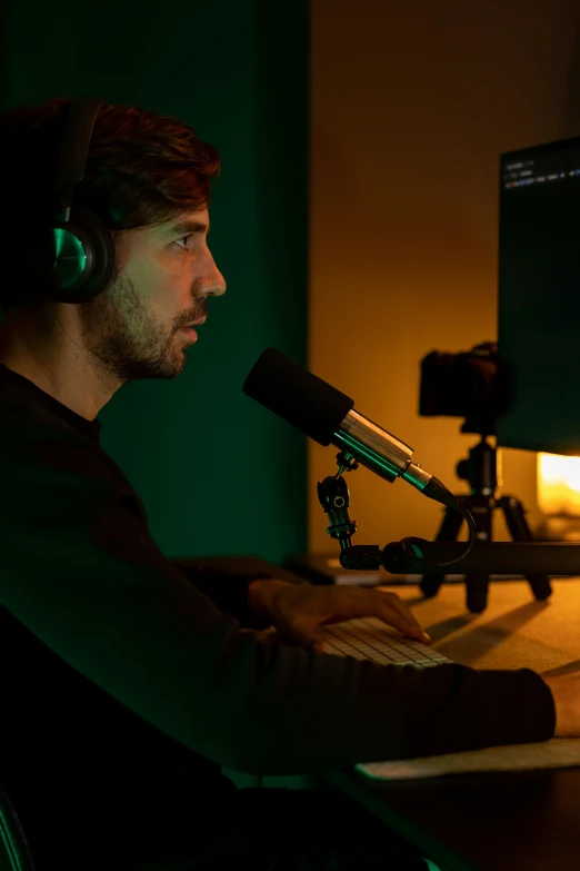 a man sitting in front of a computer next to a microphone