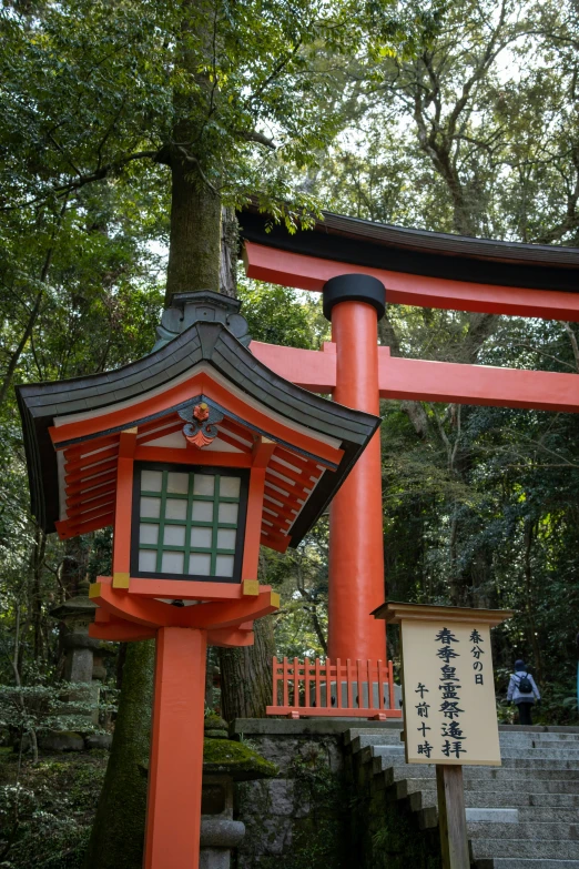 a red oriental building next to a path in the woods