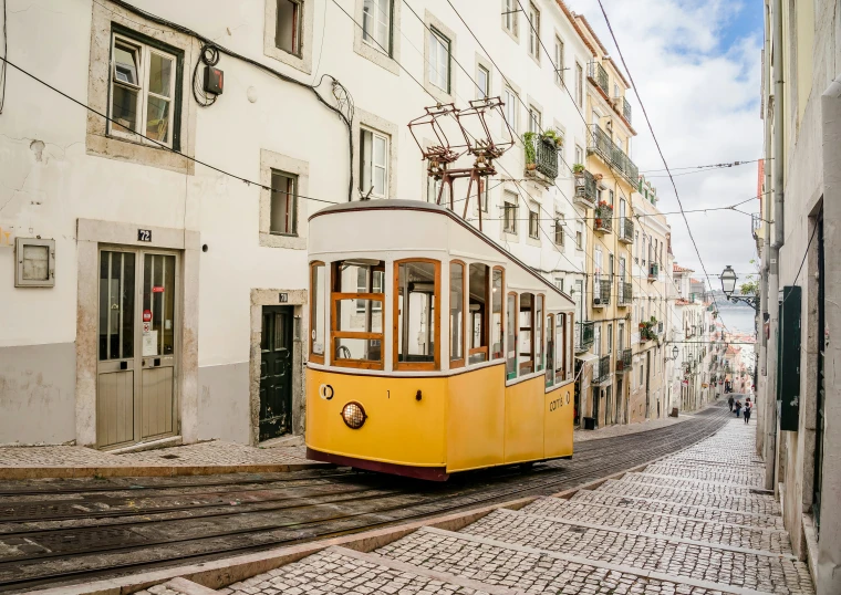 a yellow and white trolley is on a cobblestone road