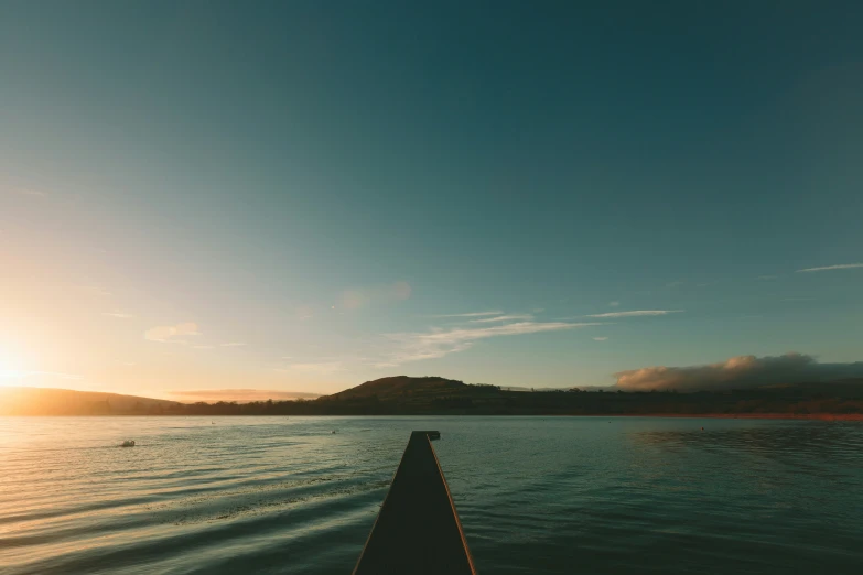 a view of the sun is rising over a lake