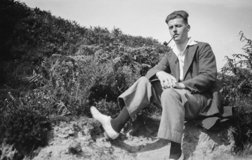 black and white po of a man sitting on a cliff
