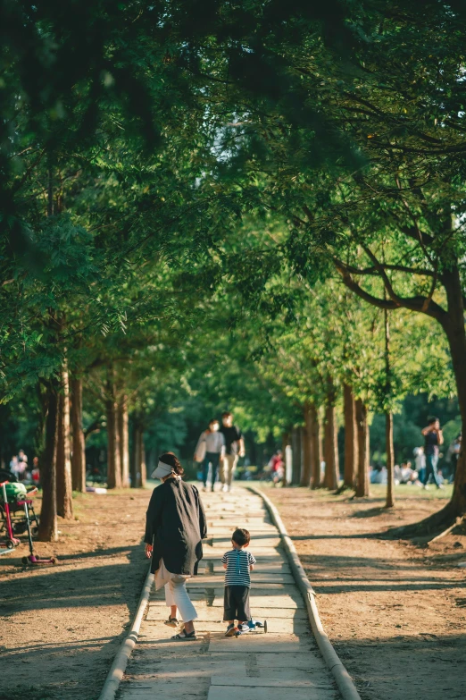 the woman and child are walking down the tree lined walkway