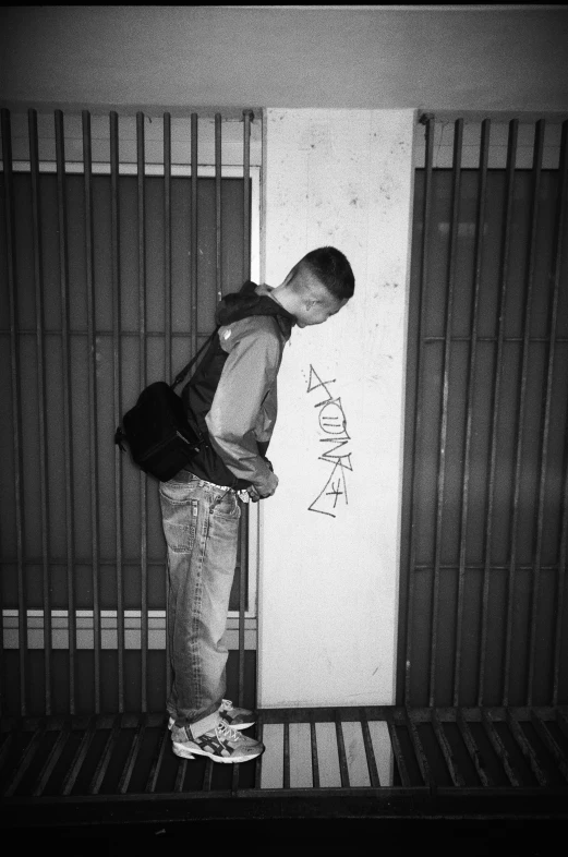 a boy is bent over while leaning against the wall