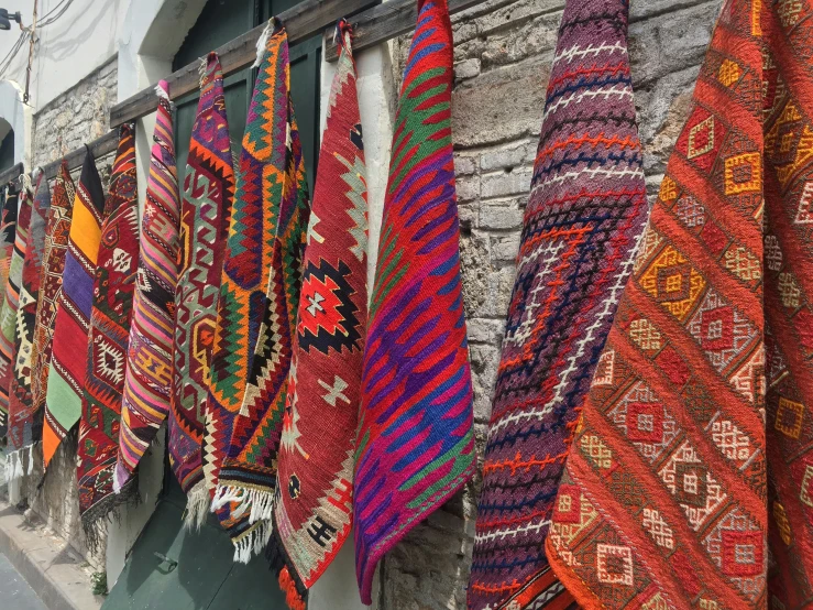 a bunch of different pieces of colorful fabrics hanging from a wall