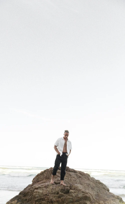 a man standing on top of a large rock near the ocean