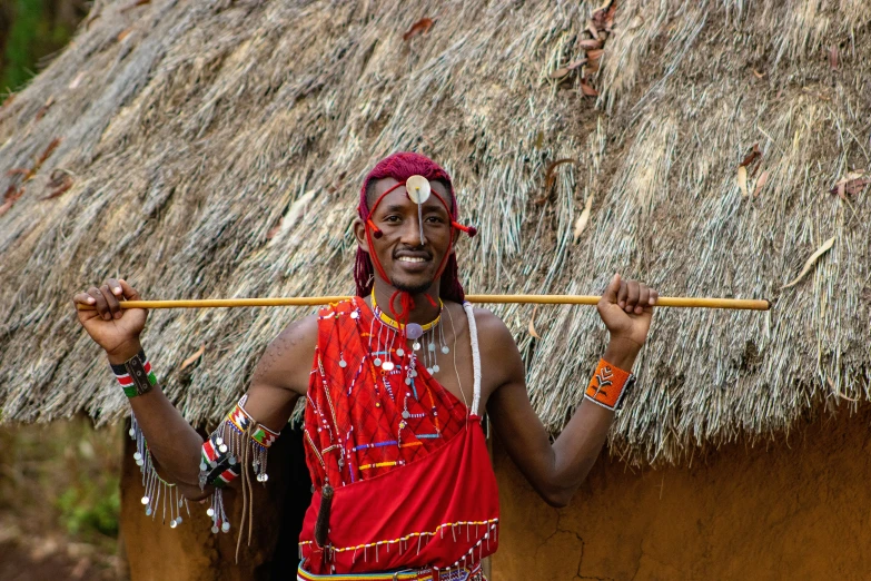 a man is holding a stick outside a hut