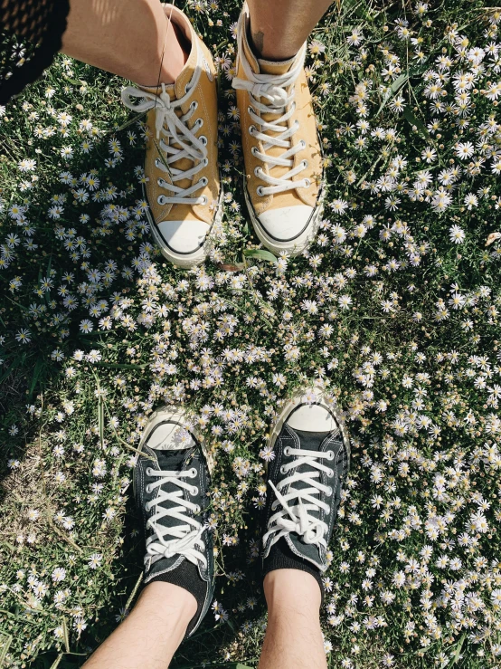 people's feet standing next to each other in a field of wild flowers