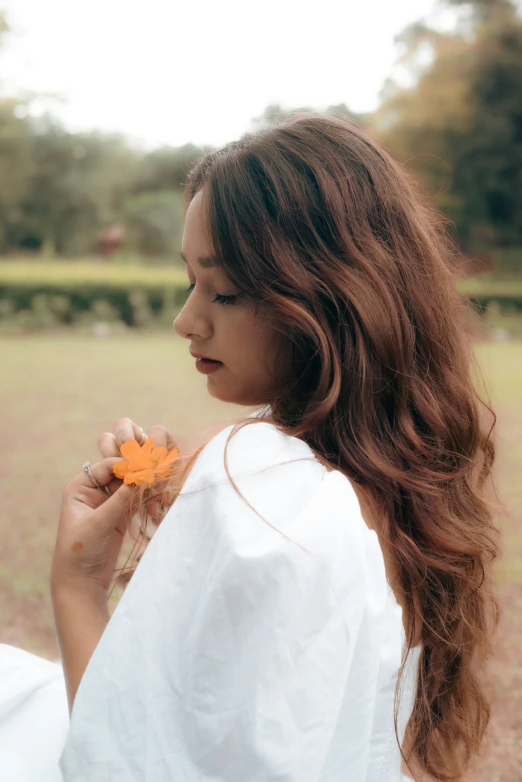 a woman in white shirt eating orange food from the ground