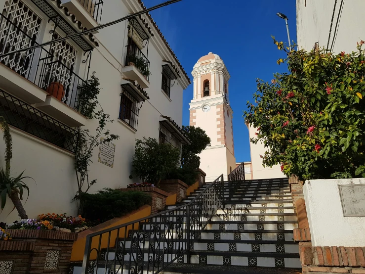 an elegant stairway with railing and planters leading to a clock tower