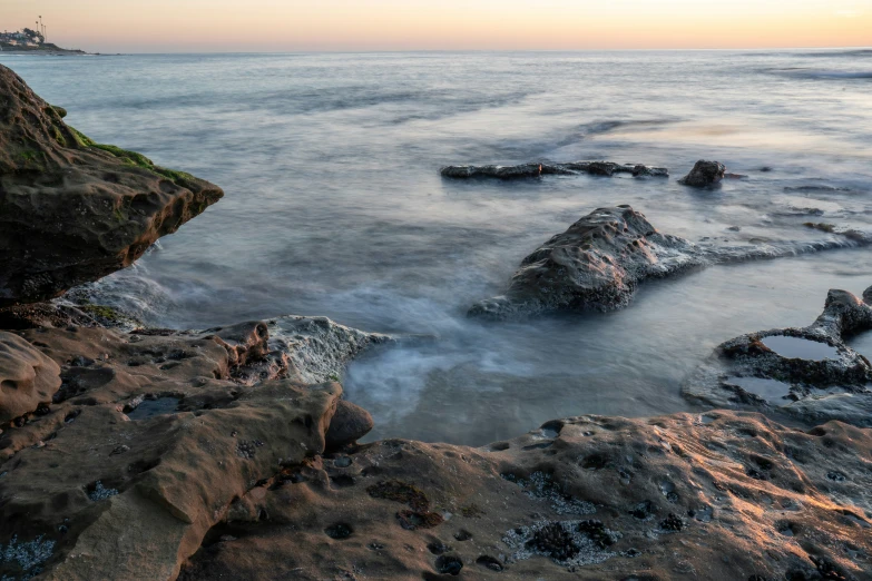 some large rocks sitting on the beach near a shore line