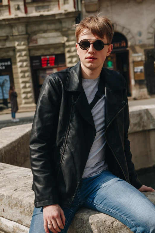 a man is sitting on the ledge near a street