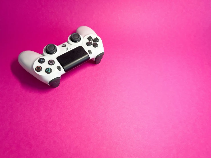 a game controller on a pink surface