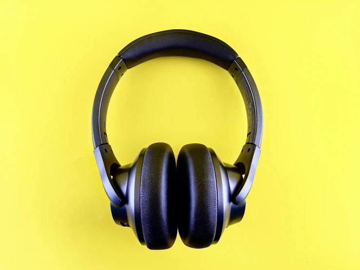 a pair of black headphones on top of yellow surface
