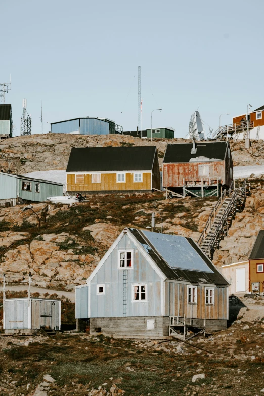 some houses on a hill with lots of grass and dirt