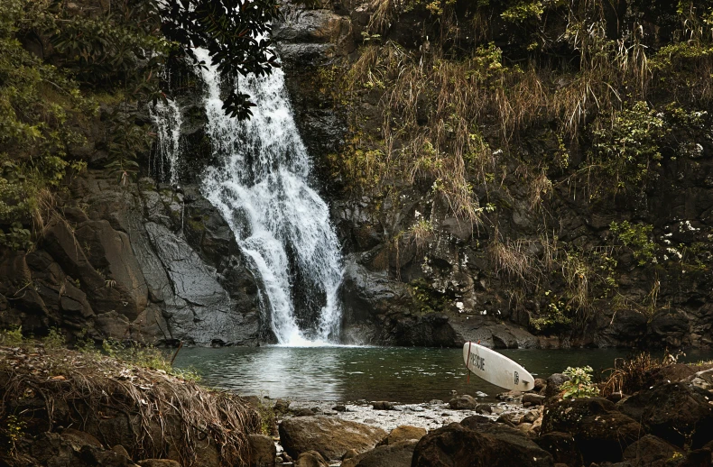 a person is lying on the rocks near a waterfall