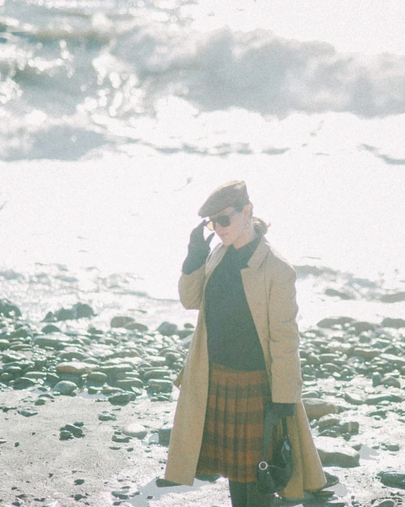 a woman standing on a beach while talking on a phone