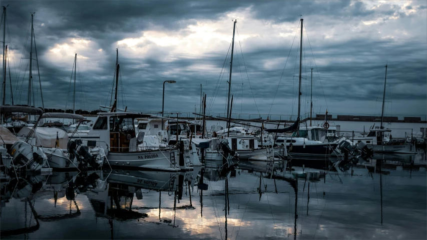many boats docked in the water with a cloudy sky above